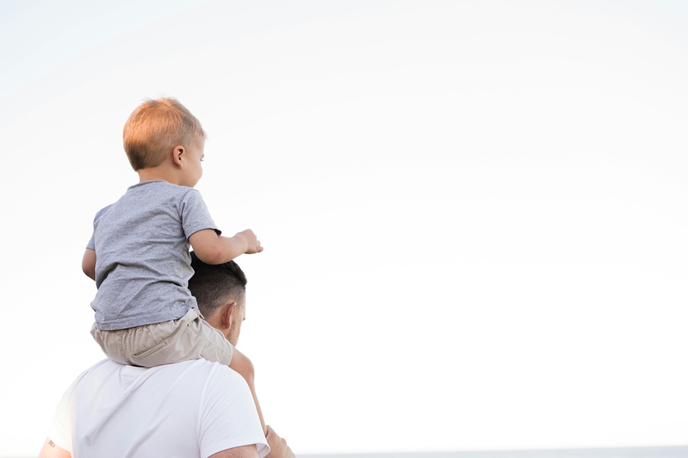 A dad carrying his young son on his shoulders