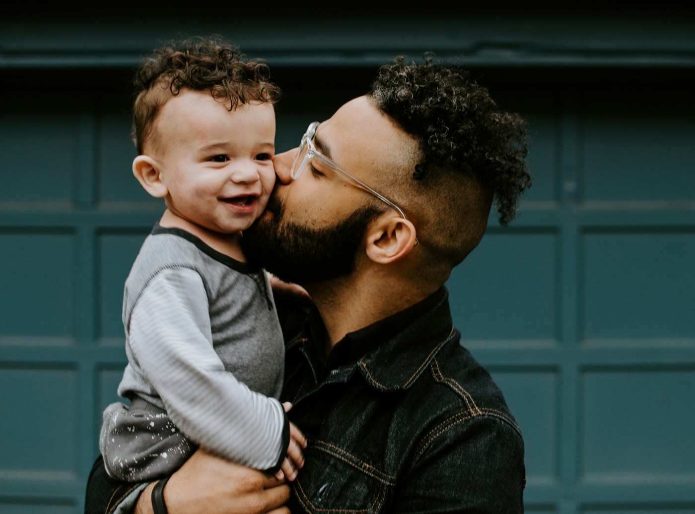 A dad kissing his toddler son on the cheek