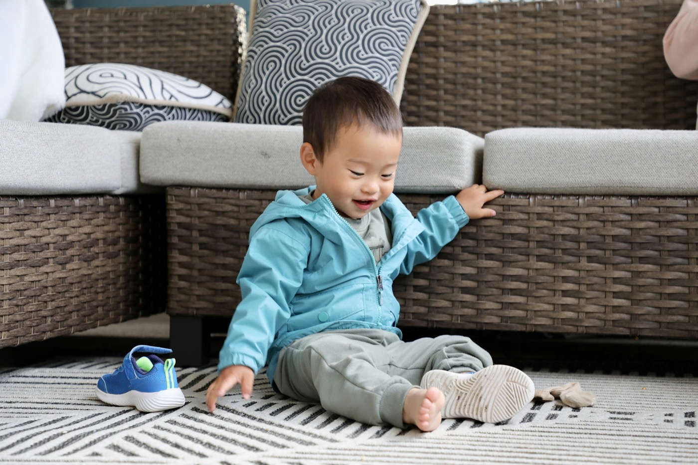 A toddler sitting on a rug beside a couch